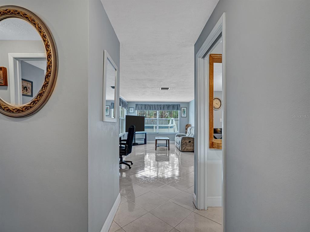 A view from a hallway looking into a living room with tile flooring and windows — 6732 WILLIAM TELL DRIVE, NEW PORT RICHEY, FL