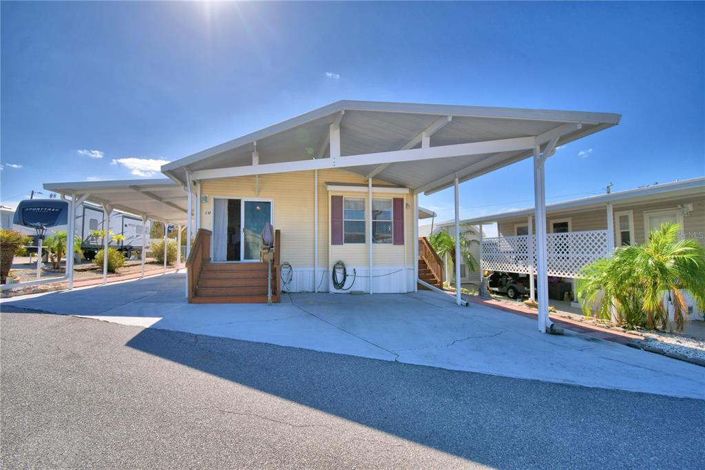 A yellow manufactured home with a large attached carport and concrete driveway — 251 PATTERSON ROAD UNIT I17, HAINES CITY, FL