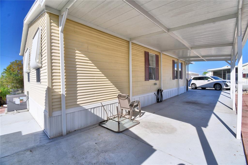 A yellow mobile home features a concrete carport and a metal patio cover — 251 PATTERSON ROAD UNIT I17, HAINES CITY, FL