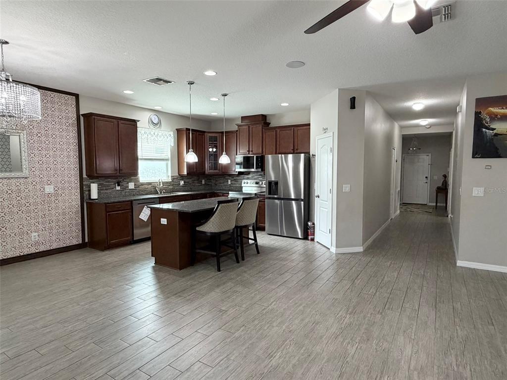 A kitchen with dark wood cabinets, stainless steel appliances, and a central island with seating — 3272 MANGROVE ISLAND DRIVE, ORLANDO, FL