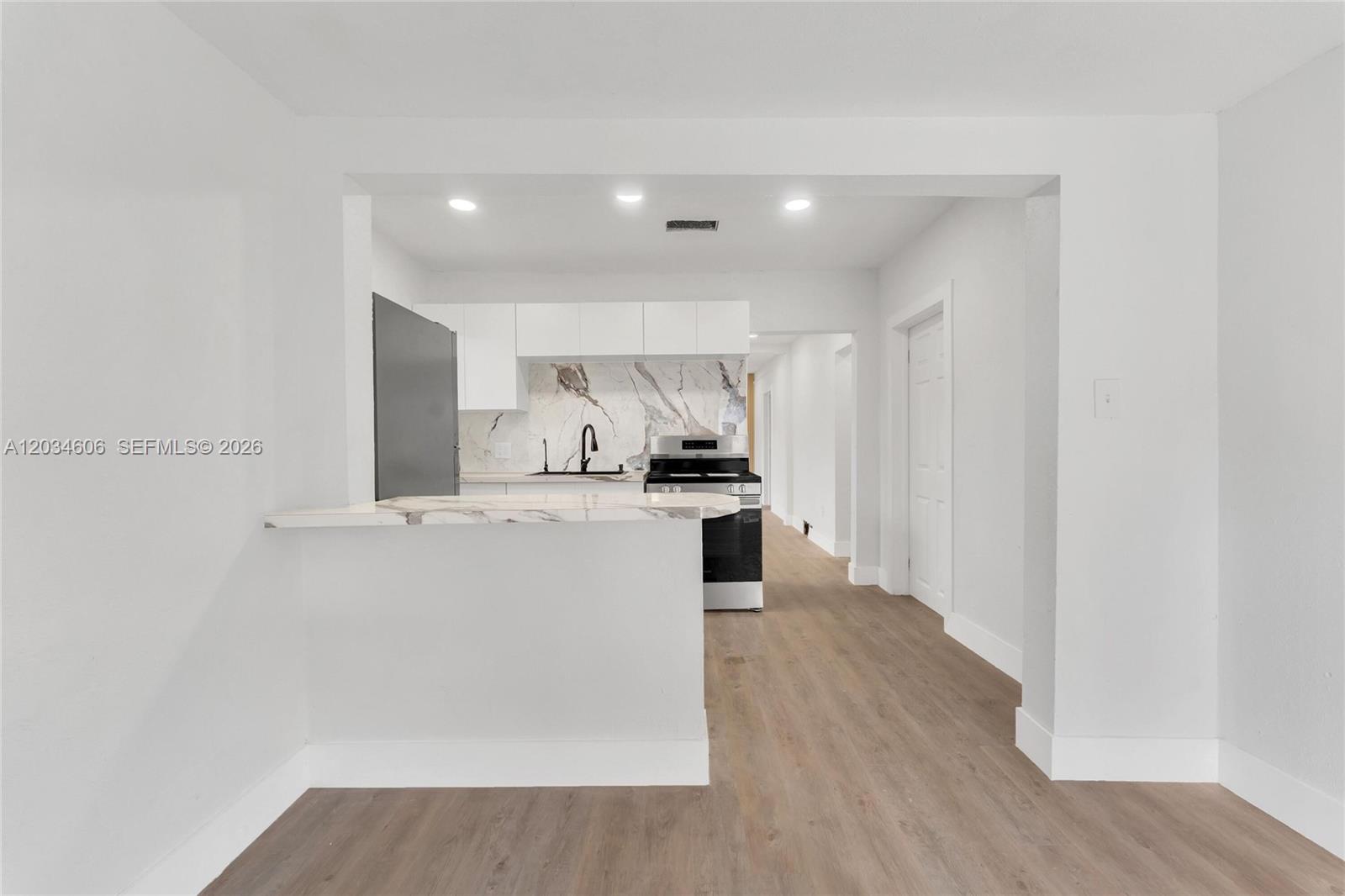 A kitchen features white cabinetry, a marble-patterned backsplash, and a breakfast bar — 2428 NW 28th St, Miami FL 33142, MIAMI, FL