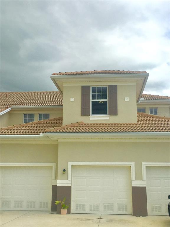 The exterior of a multi-car garage features tan stucco walls, brown shutters, and tile roofing — 17084 ACAPULCO ROAD UNIT 223, PUNTA GORDA, FL
