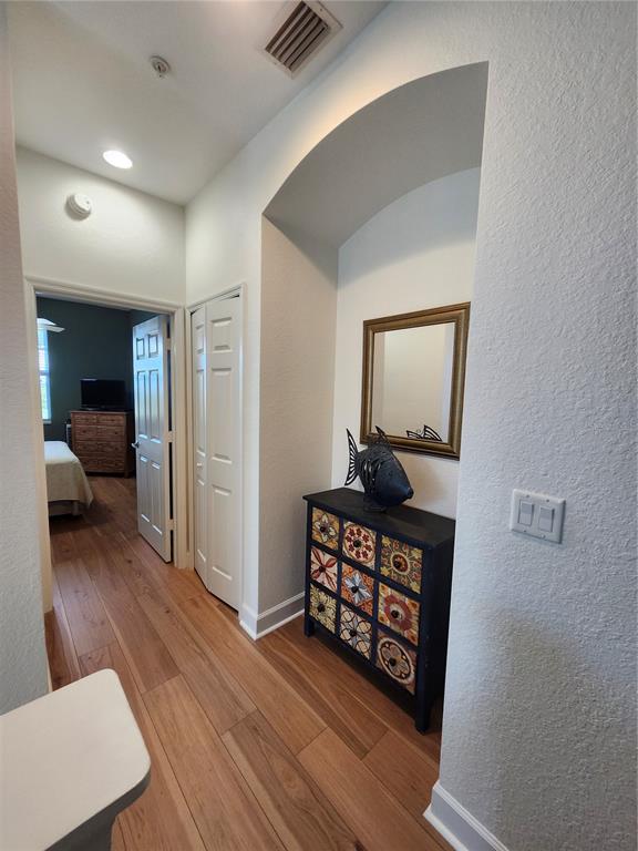 A hallway features wood-look flooring, a decorative chest, a wall mirror, and an arched alcove — 17084 ACAPULCO ROAD UNIT 223, PUNTA GORDA, FL
