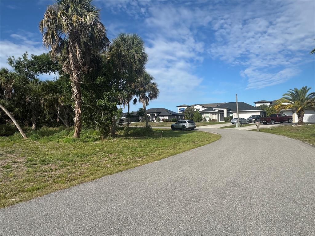 A vacant grassy lot sits next to a paved road with houses in the background — Lot 1 MULGRAVE AVENUE, NORTH PORT, FL