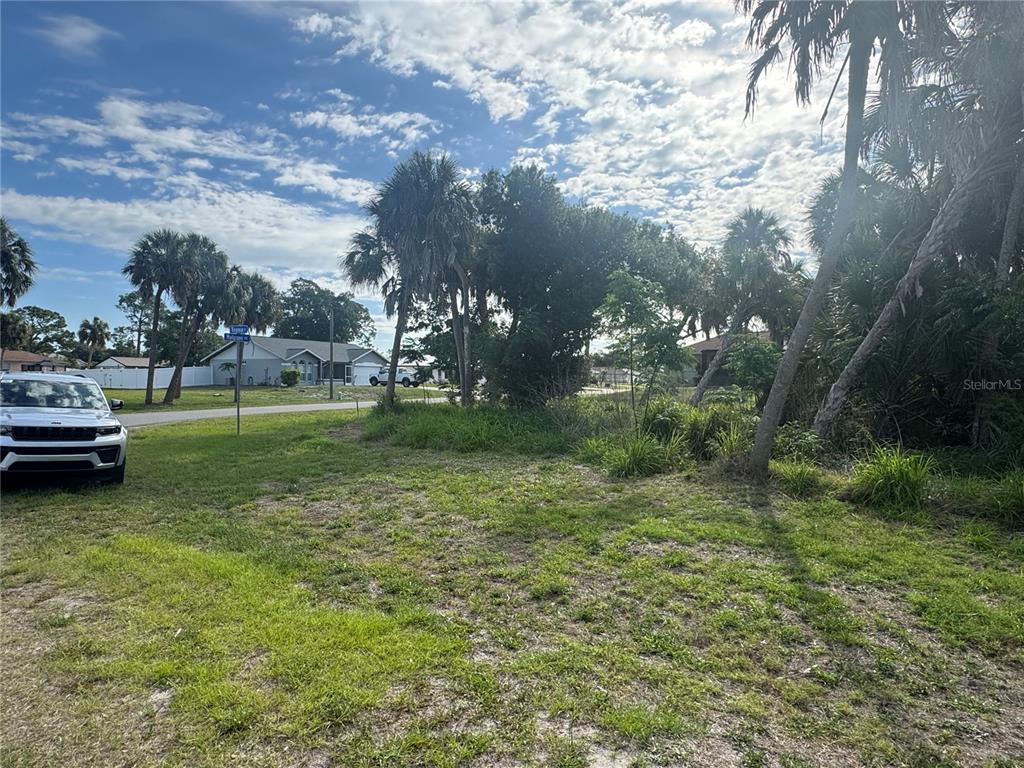 A vacant, grassy lot with scattered palm trees and vegetation under a cloudy blue sky — Lot 1 MULGRAVE AVENUE, NORTH PORT, FL