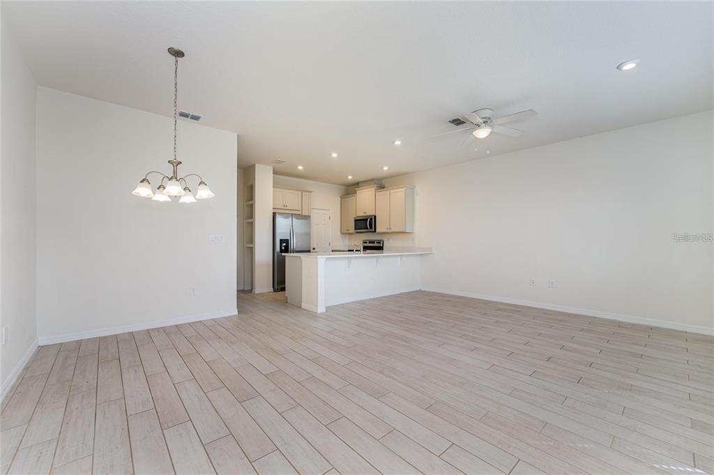 An open-concept kitchen and dining area features light wood-look tile flooring and white cabinetry — 2962 FIREBUSH WAY, CLERMONT, FL