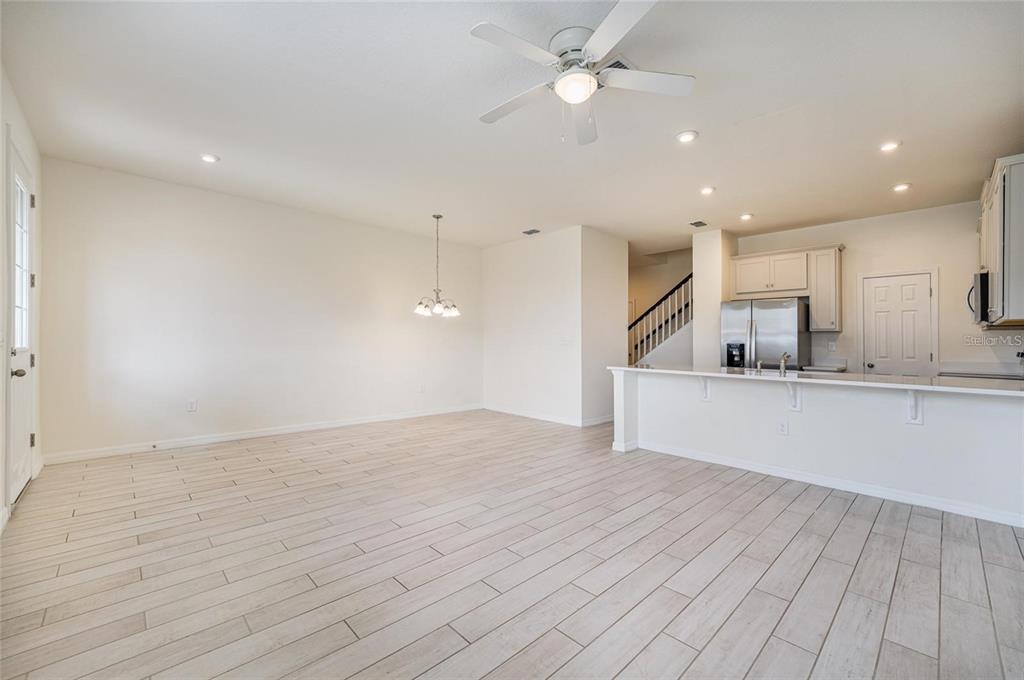An open-concept kitchen and dining area features light wood-look tile flooring and a ceiling fan — 2962 FIREBUSH WAY, CLERMONT, FL