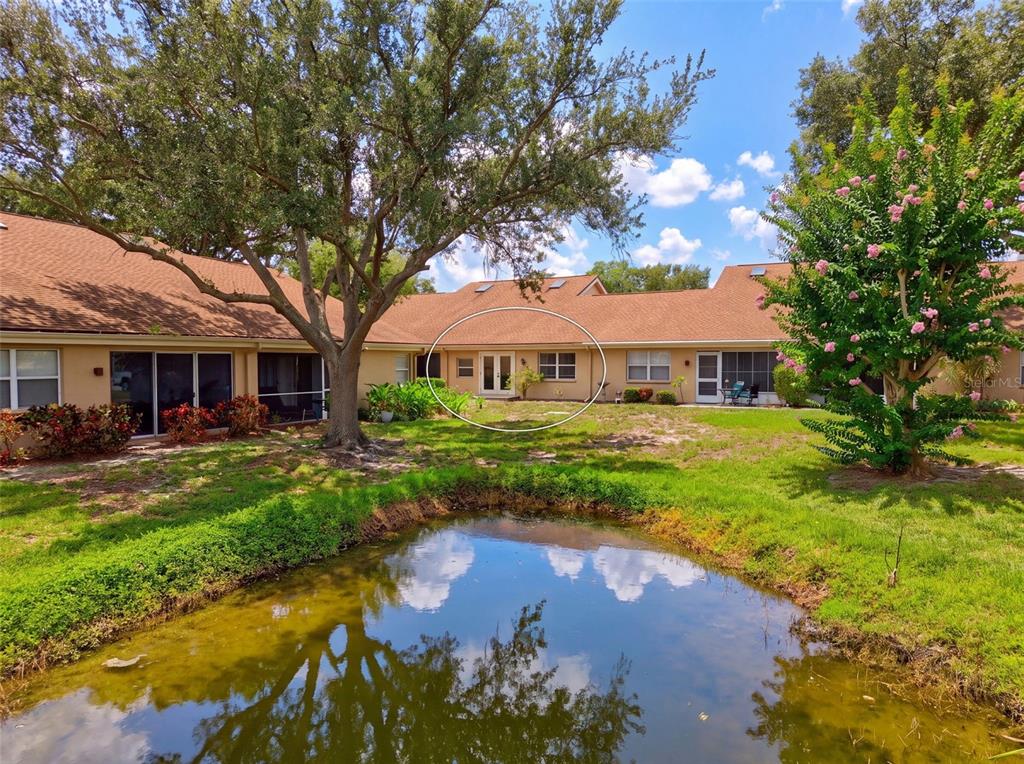 A view of a tan building exterior with a pond in the foreground — 5626 MONTE ROSSO ROAD, SARASOTA, FL