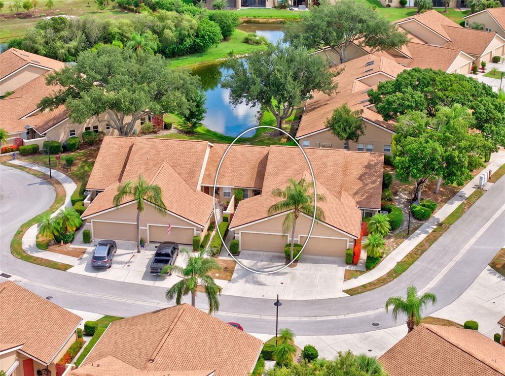 An aerial view shows a tan townhouse with a brown shingled roof and palm trees — 5626 MONTE ROSSO ROAD, SARASOTA, FL