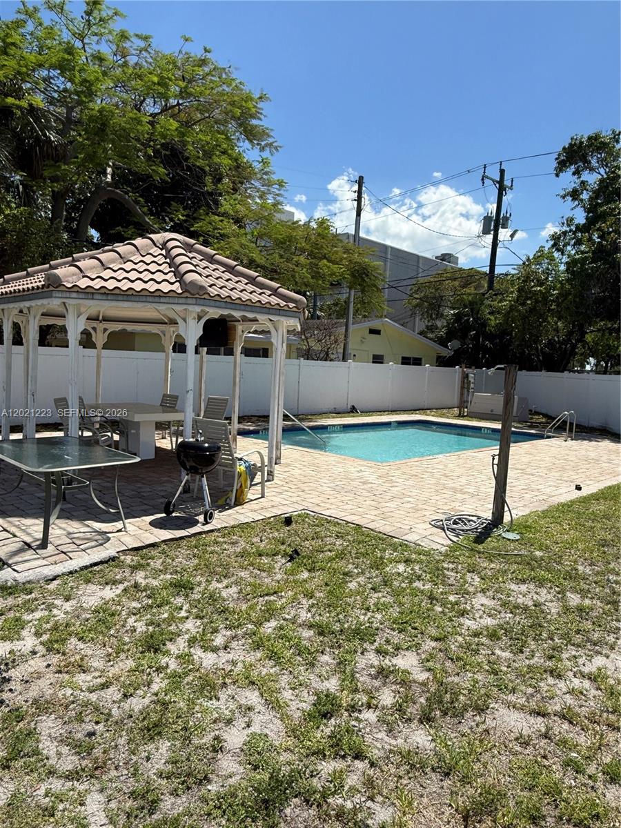 A backyard features a swimming pool, a gazebo with patio furniture, and a grill — 1247 NE 23rd Ave, Pompano Beach FL 33062, POMPANO BEACH, FL