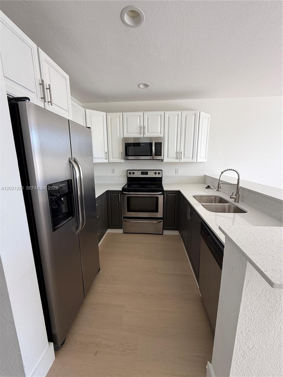 A kitchen features white upper cabinets, dark lower cabinets, stainless steel appliances, and quartz countertops — 1247 NE 23rd Ave, Pompano Beach FL 33062, POMPANO BEACH, FL