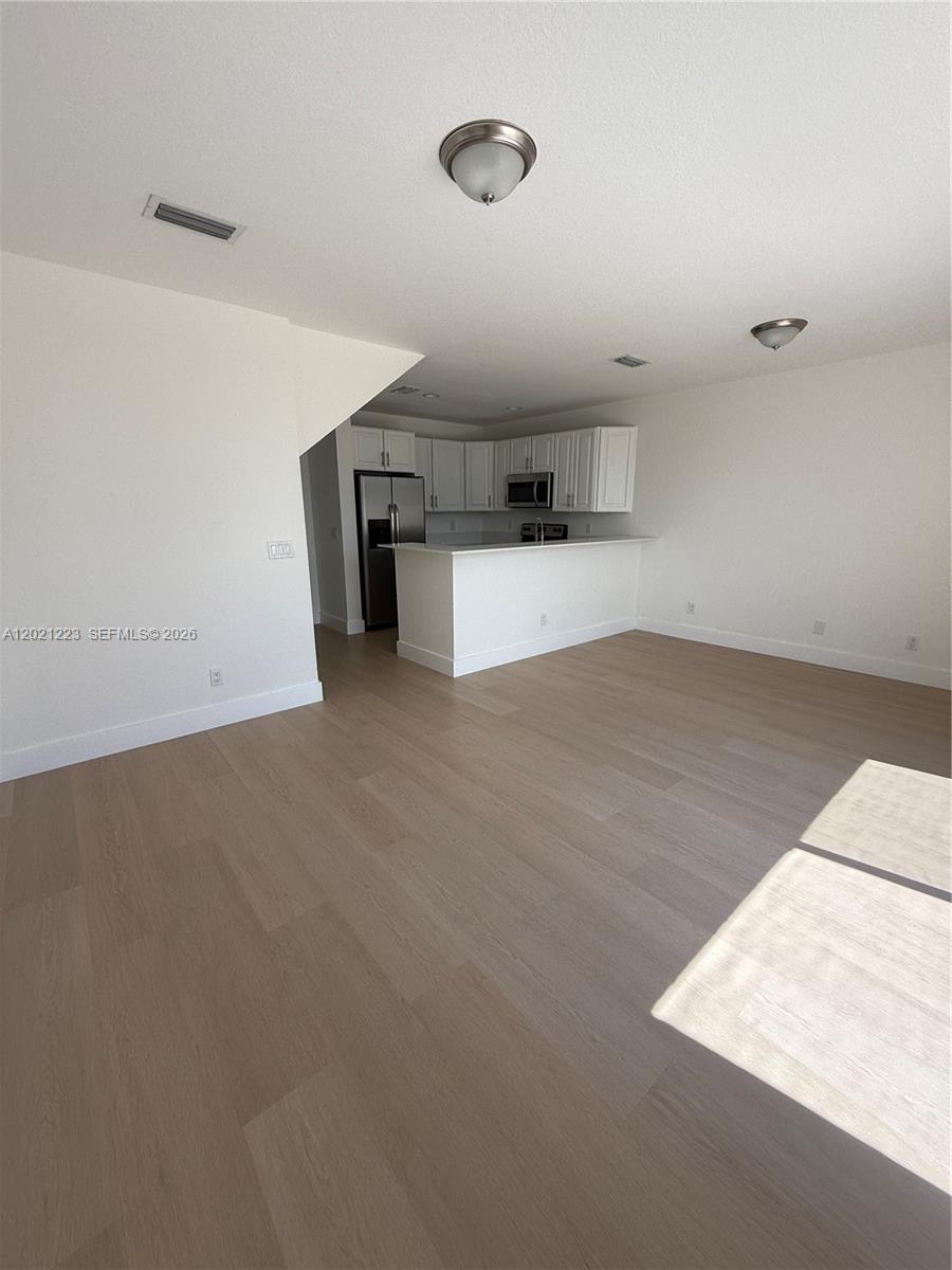 An open-concept kitchen with white cabinets and a breakfast bar overlooks a living area — 1247 NE 23rd Ave, Pompano Beach FL 33062, POMPANO BEACH, FL