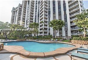 A swimming pool sits in front of a tall, multi-story residential building with balconies — 2000 Towerside # 309, Miami FL 33138, MIAMI, FL