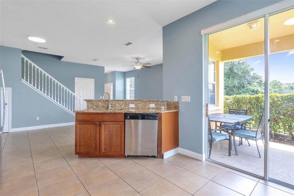 A kitchen island with a stainless steel dishwasher sits before a sliding glass patio door — 906 ASSEMBLY COURT, KISSIMMEE, FL