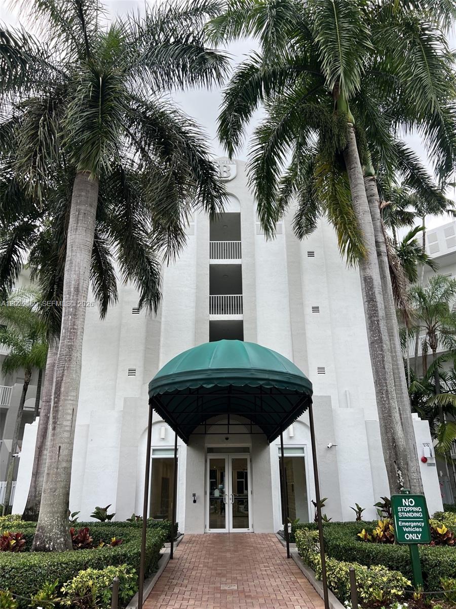 A white multi-story building entrance features a green awning, palm trees, and a brick walkway — 10750 NW 66th St # 401, Doral FL 33178, DORAL, FL