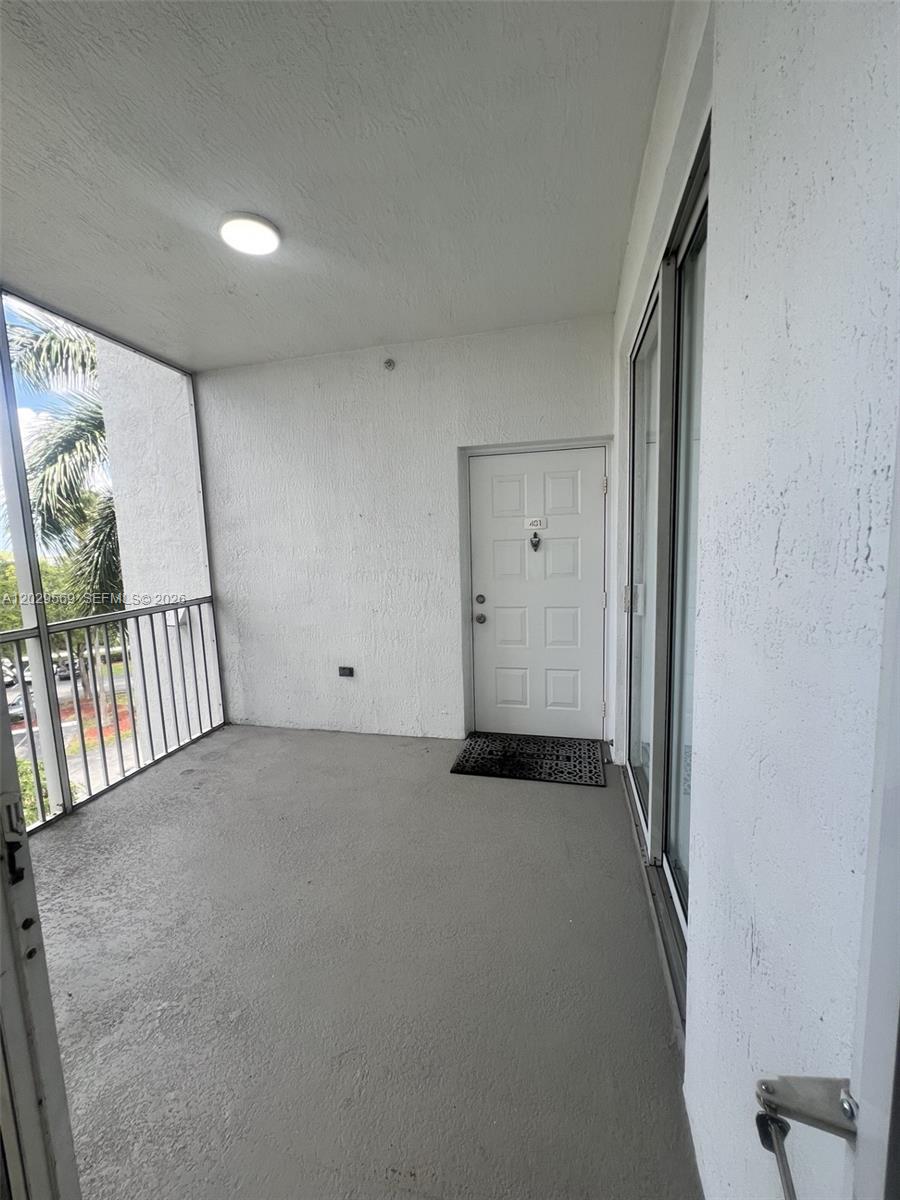 A covered balcony features a white door, a light fixture, and a metal railing — 10750 NW 66th St # 401, Doral FL 33178, DORAL, FL