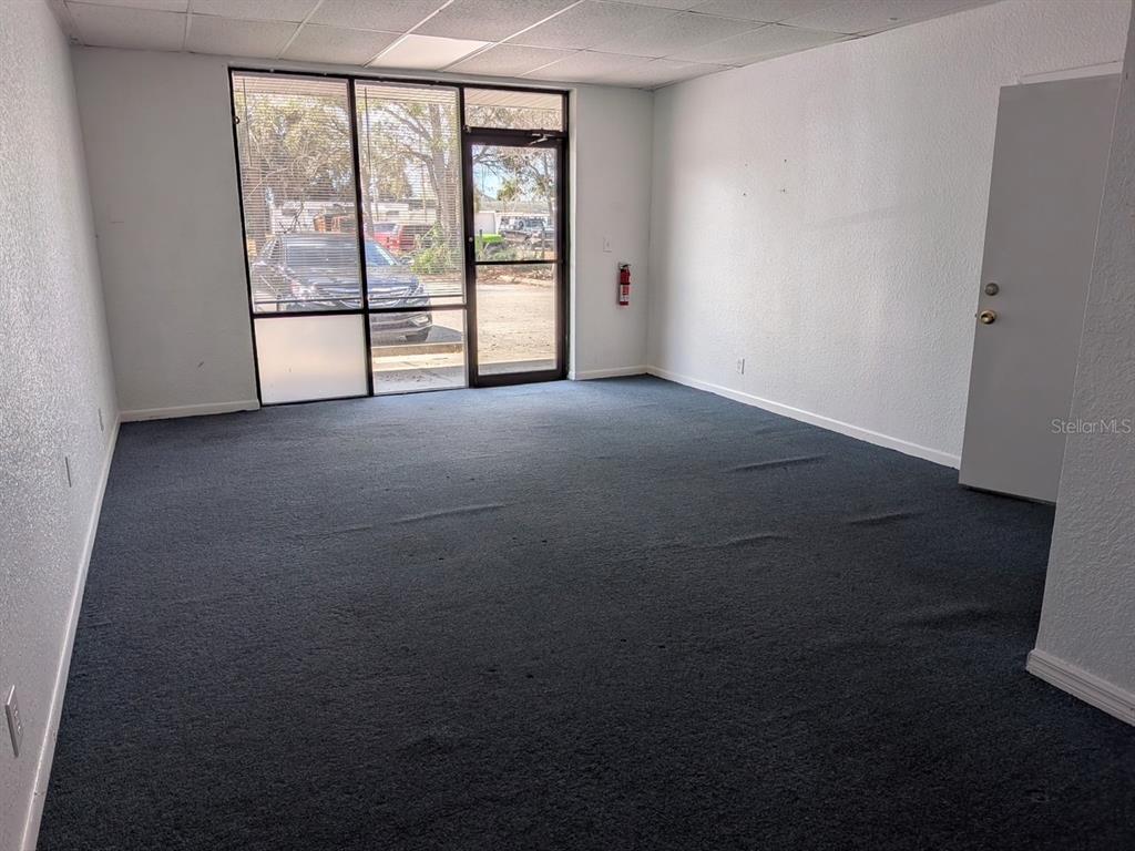 An empty office space features dark gray carpeting, white walls, and a large glass-paneled door — 5630 PARK BOULEVARD N UNIT A & B, PINELLAS PARK, FL