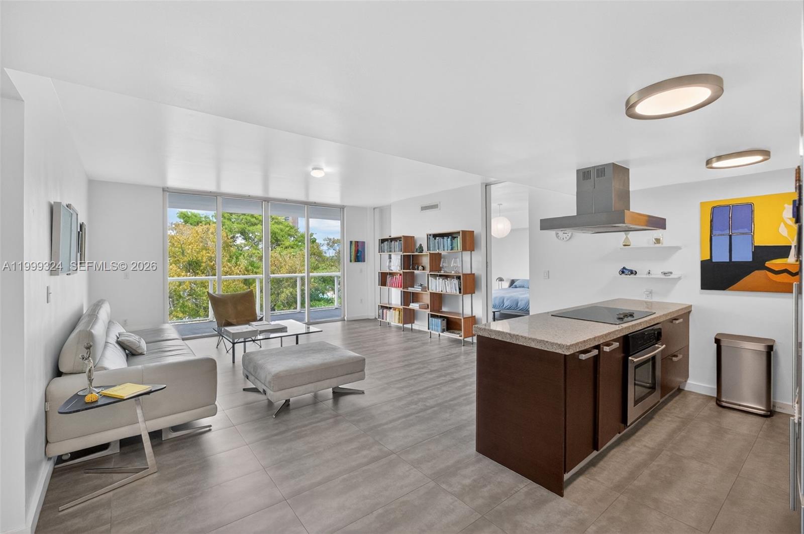 An open-concept living area features a kitchen island, gray tile flooring, and floor-to-ceiling windows — 720 NE 62nd St # 404, Miami FL 33138, MIAMI, FL