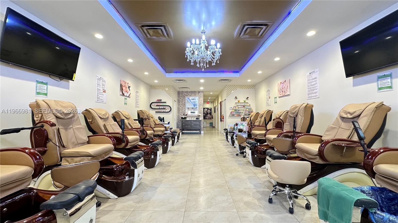 A nail salon features rows of pedicure chairs, a central chandelier, and two wall-mounted televisions — SW 40 St, Miami FL 33165, MIAMI, FL