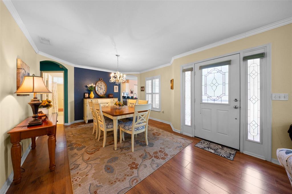 A dining room with a wooden table, chairs, area rug, and a front entryway door — 7240 SW 115TH PLACE, OCALA, FL