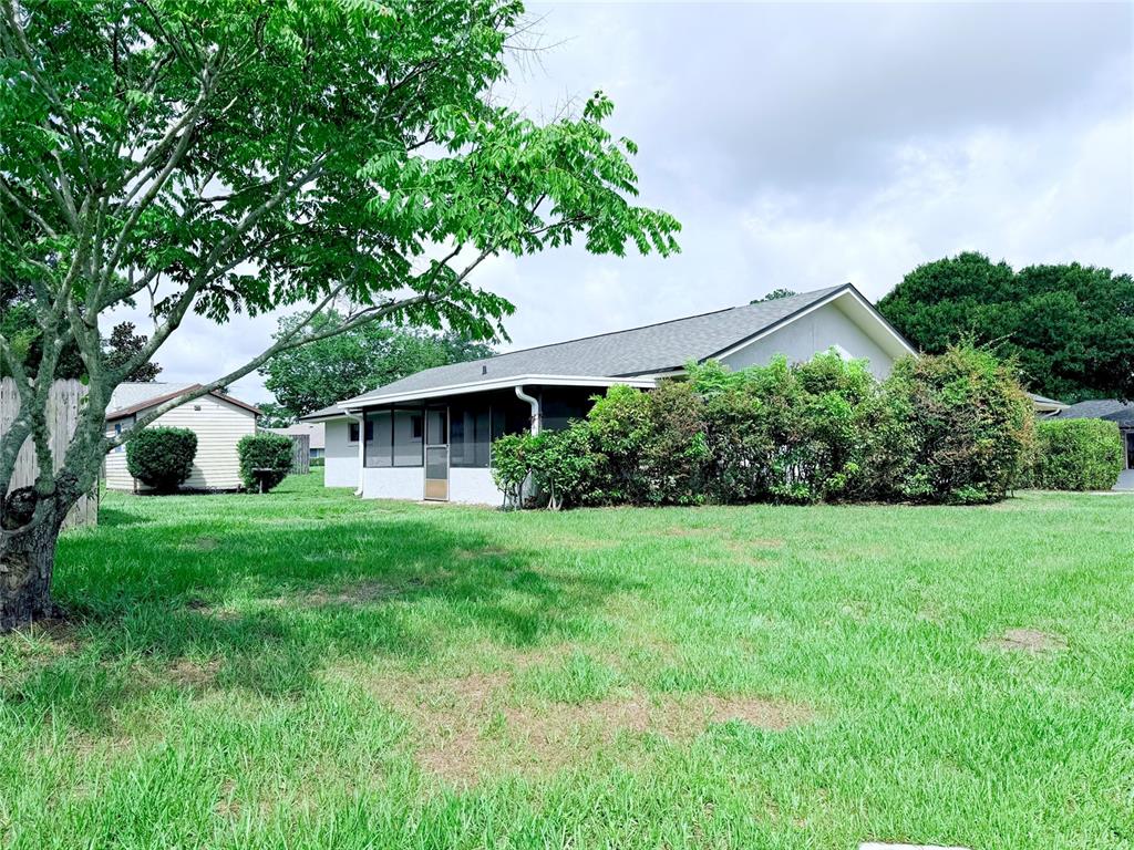 A white house with a screened-in porch stands behind a large tree and lawn — 298 QUAIL COURT, CASSELBERRY, FL