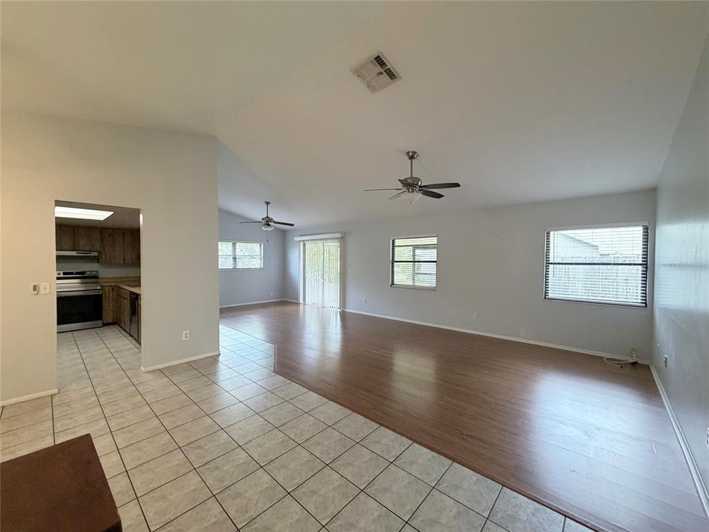 A spacious living area with wood-look flooring and an adjacent tiled kitchen — 298 QUAIL COURT, CASSELBERRY, FL