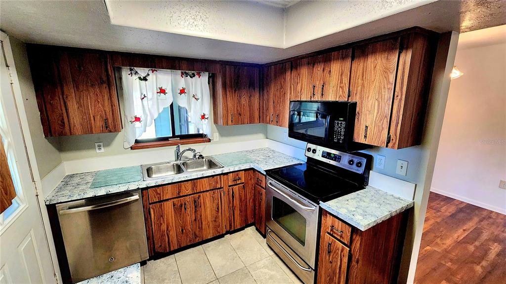A kitchen with wood cabinets, stainless steel appliances, and light-colored speckled countertops — 10405 SW 99TH AVENUE, OCALA, FL