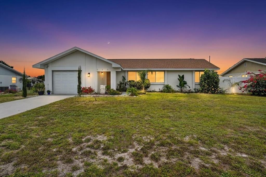 A single-story house with a white exterior, a one-car garage, and a grassy front yard — 885 FAIRFAX TERRACE NW, PORT CHARLOTTE, FL