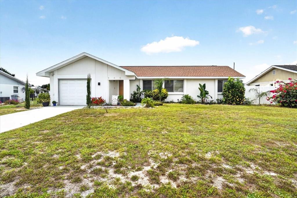 A single-story house with a white exterior, a one-car garage, and a large front lawn — 885 FAIRFAX TERRACE NW, PORT CHARLOTTE, FL