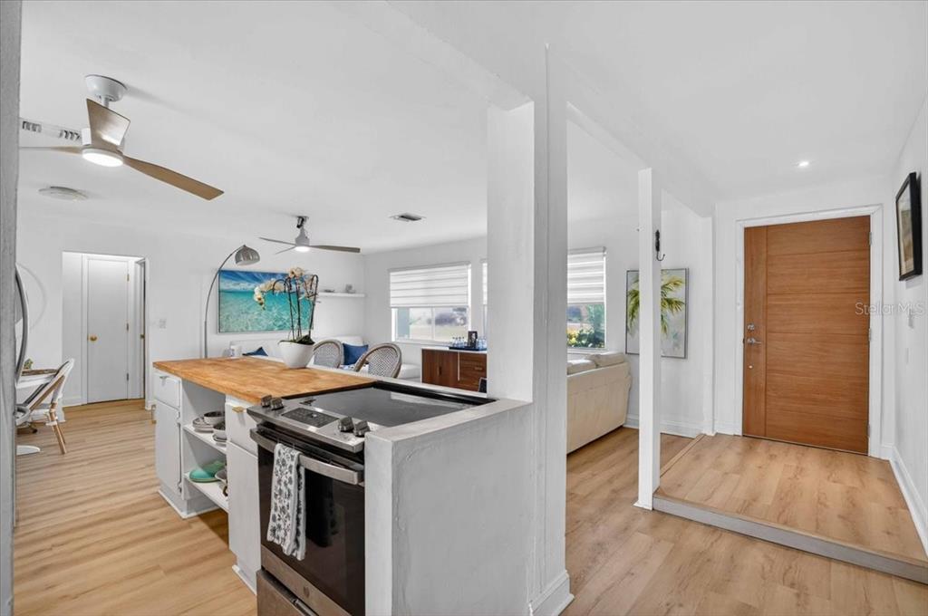 A kitchen with a wood countertop island overlooks a living area near an entryway door — 885 FAIRFAX TERRACE NW, PORT CHARLOTTE, FL