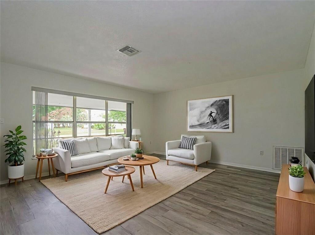 A living room features a white sofa, armchair, two round coffee tables, and wood flooring — 136 16th Avenue, Vero Beach FL 32962, VERO BEACH, FL