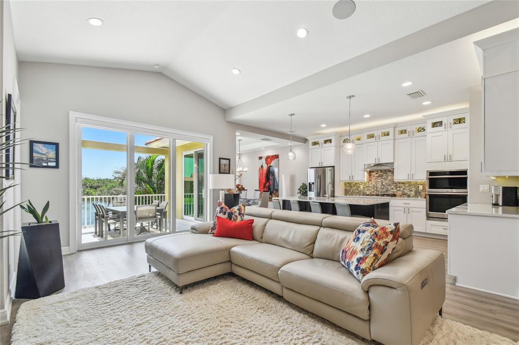 A living room with a beige sectional sofa, white kitchen cabinetry, and a sliding glass door — 17 FRANKLIN COURT S UNIT C, ST PETERSBURG, FL