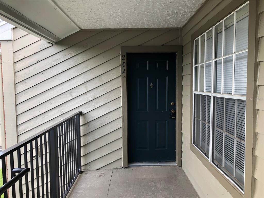 A dark blue front door with the number 202 is on a covered apartment balcony — 9100 DR MARTIN LUTHER KING JR STREET N UNIT 202, ST PETERSBURG, FL