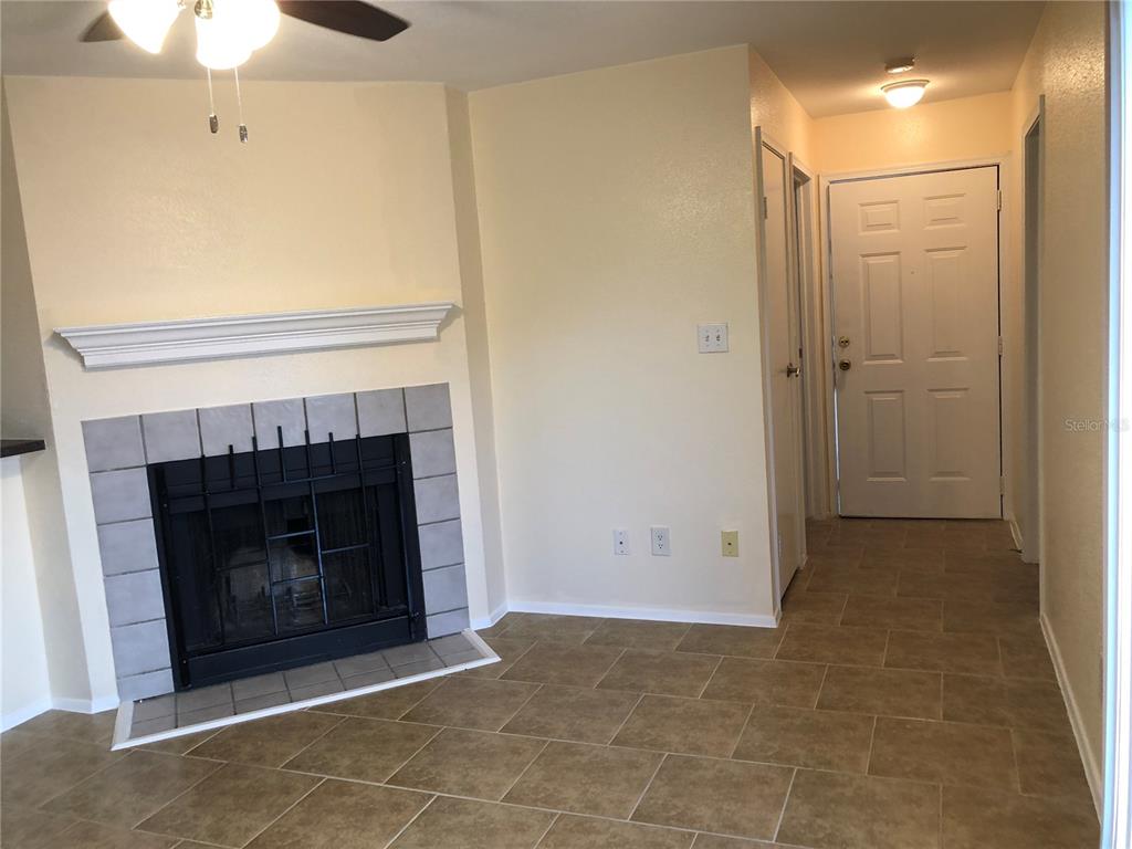 A living room features a tiled fireplace, beige walls, and a white front door — 9100 DR MARTIN LUTHER KING JR STREET N UNIT 202, ST PETERSBURG, FL