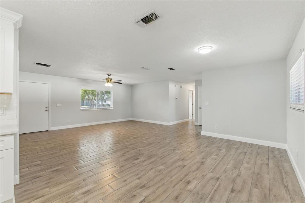 A spacious, light-filled living room features light gray walls and wood-look tile flooring — 8255 PAMLICO STREET, ORLANDO, FL