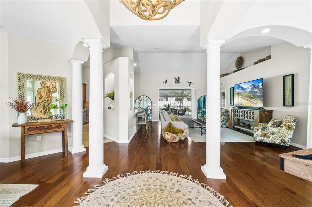 A view from a foyer with columns looking into a living room with hardwood floors — 116 ERIC DRIVE, PALM COAST, FL