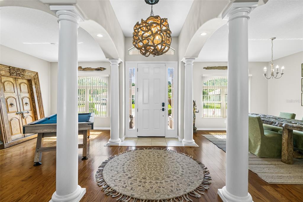 An entryway features a circular rug, a decorative chandelier, and columns separating a dining area — 116 ERIC DRIVE, PALM COAST, FL
