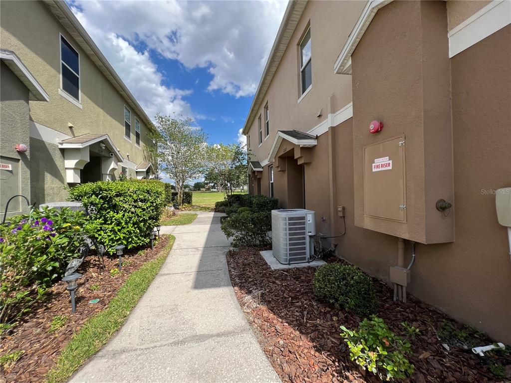 A concrete walkway leads between two multi-story residential buildings with exterior fire riser cabinets — 2137 BETSY ROSS LANE UNIT 2137, ST CLOUD, FL
