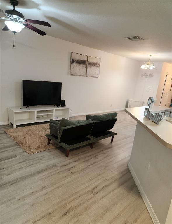 A living room features light wood-look flooring, a white media console, and a green sofa — 9611 CARLSDALE DRIVE, RIVERVIEW, FL