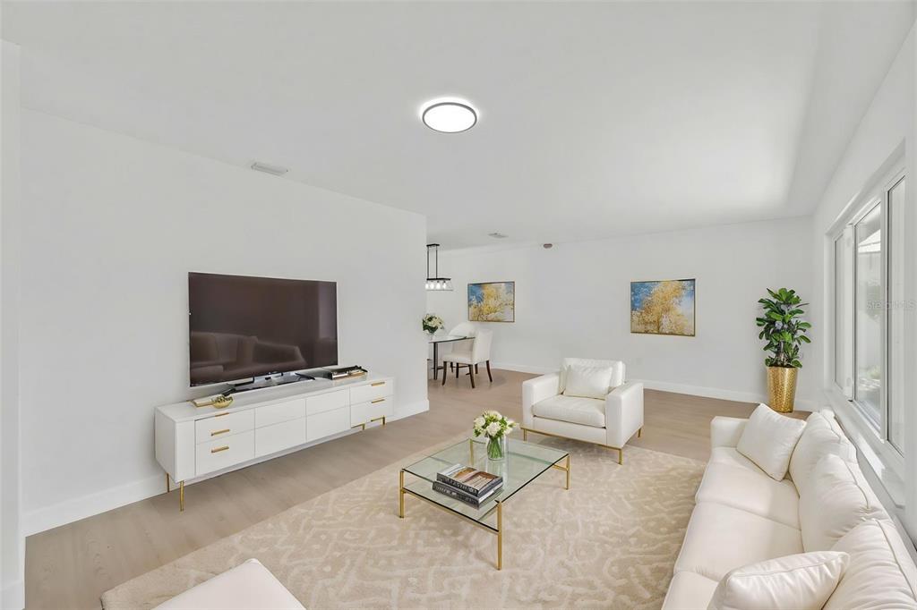 A bright living room features white furniture, a glass coffee table, and light wood flooring — 11180 113TH AVENUE, LARGO, FL
