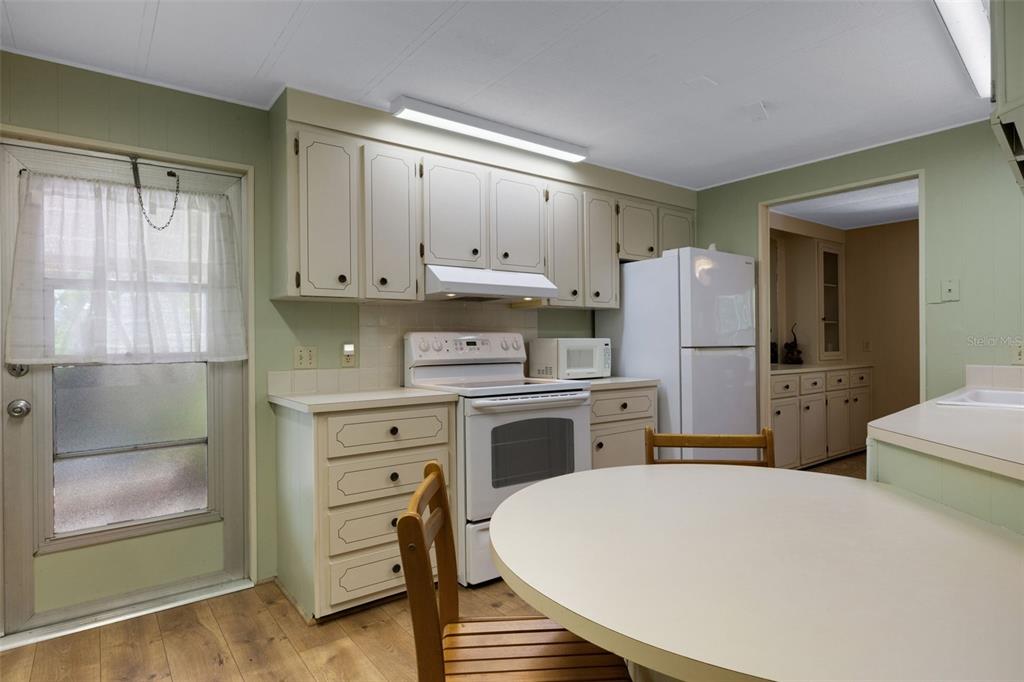 A kitchen features light green walls, white cabinets, a white stove, and a round table — 98 CEDAR ELM DRIVE UNIT 32, SAFETY HARBOR, FL