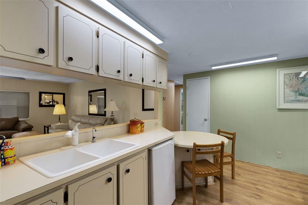 A kitchen with white cabinets, a double sink, and a small dining table — 98 CEDAR ELM DRIVE UNIT 32, SAFETY HARBOR, FL