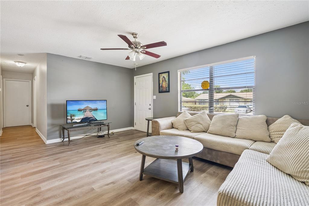 A living room features gray walls, wood-look flooring, a ceiling fan, and a sectional sofa — 1691 LUCY TERRY AVENUE, APOPKA, FL