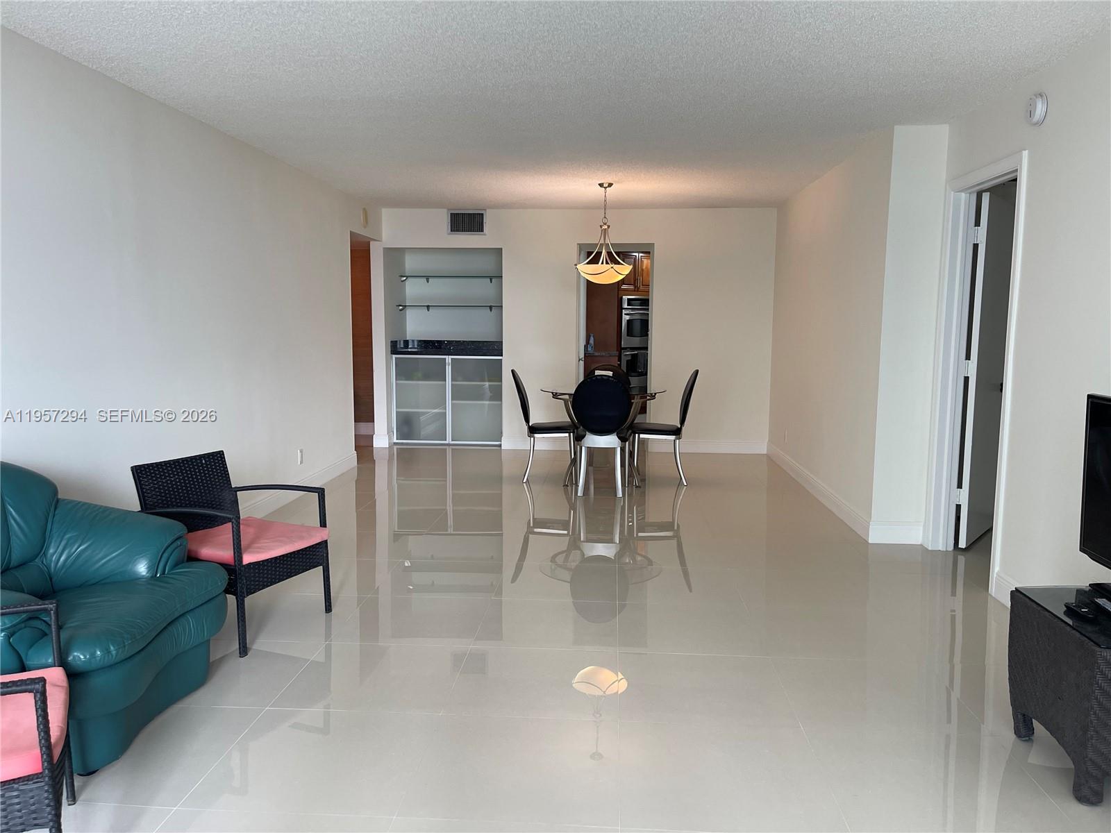 A dining area with a glass table and chairs sits adjacent to a living space — 1370 S Ocean Blvd # 903, Pompano Beach FL 33062, POMPANO BEACH, FL