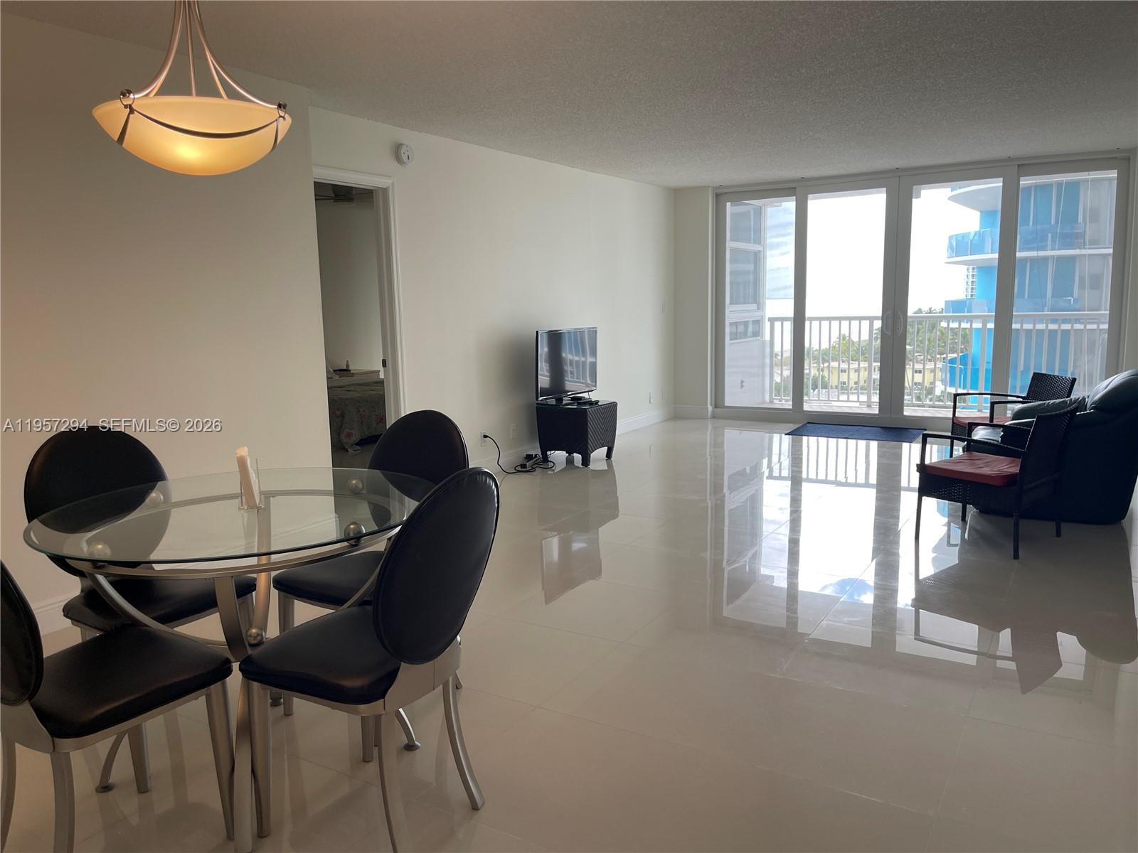 A dining area with a glass table and chairs opens into a living room with tile floors — 1370 S Ocean Blvd # 903, Pompano Beach FL 33062, POMPANO BEACH, FL