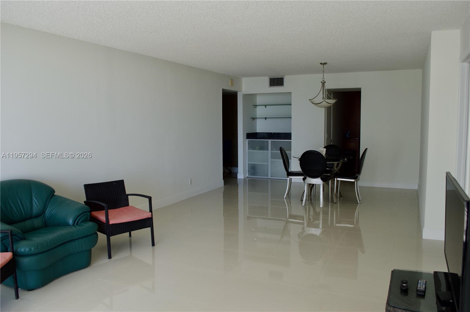 A living and dining area features light tile flooring, a teal sofa, and a wet bar — 1370 S Ocean Blvd # 903, Pompano Beach FL 33062, POMPANO BEACH, FL