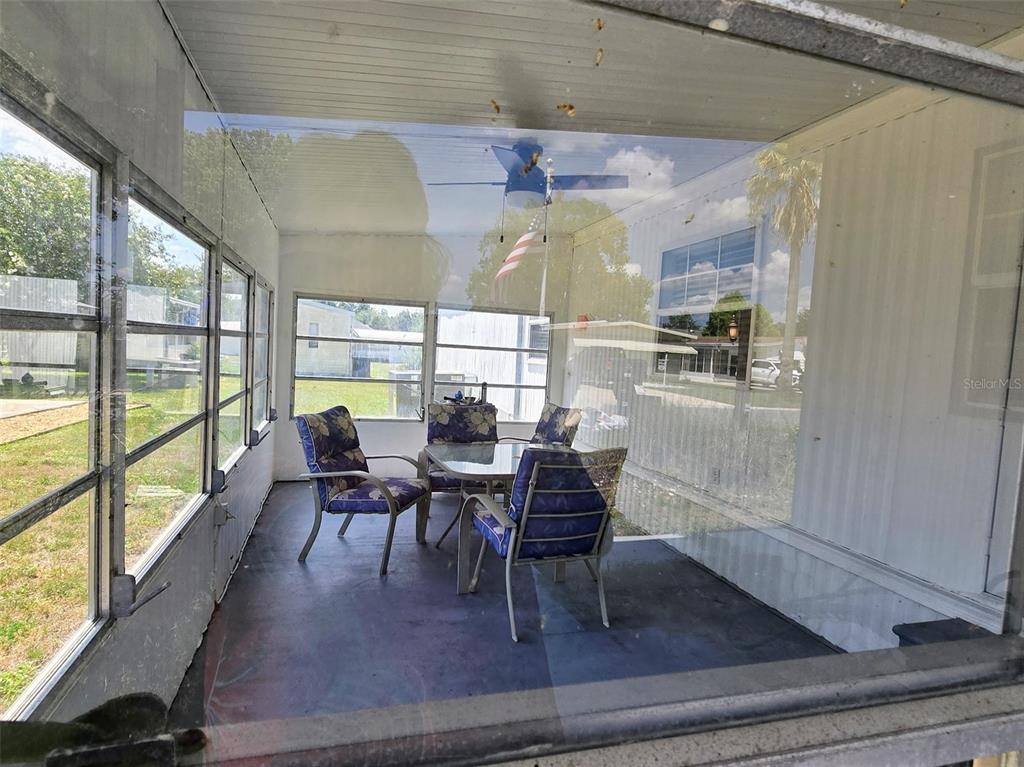 A screened-in porch features a dining set with four chairs on a concrete floor — 730 ROYAL PALM AVENUE, LADY LAKE, FL