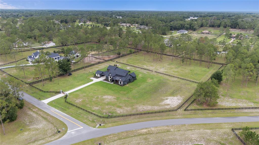 An aerial view shows a dark-roofed house with a long driveway on a large, fenced lot — 23741 RIDGE LINK ROAD, EUSTIS, FL