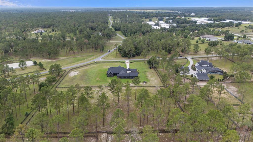 An aerial view shows a dark-roofed house situated on a large, wooded rural lot — 23741 RIDGE LINK ROAD, EUSTIS, FL