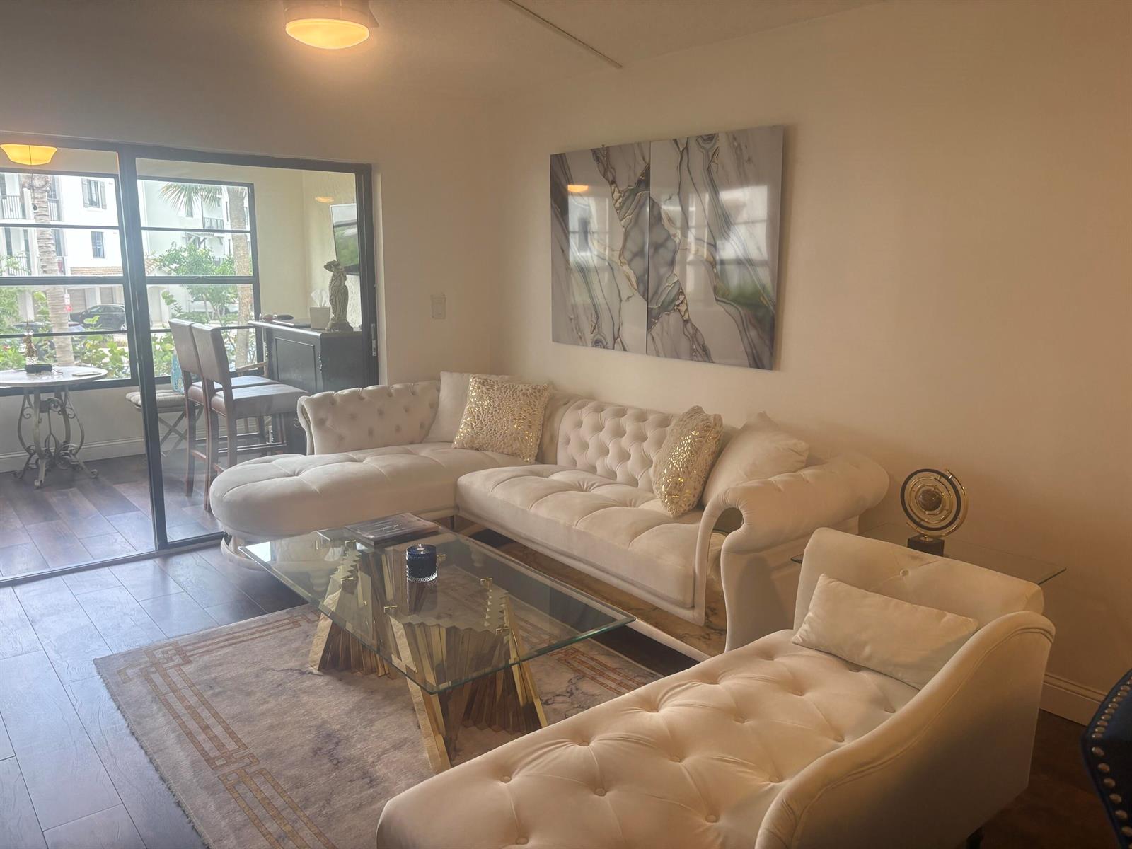 A living room features a tufted white sectional, glass coffee table, and a balcony view — 9355 SW 8th Street # 225, Boca Raton FL 33428, BOCA RATON, FL